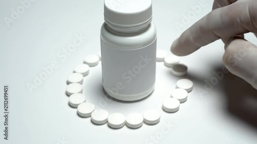 Healthcare Concept Featuring Pills And Pill Bottle With Hand In Glove Pointing On Isolated Plain Background