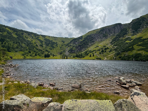 Scenic Mały Staw Mountain Lake in the Karkonosze Mountains with Crystal Water, Green Slopes and Dramatic Summer Sky