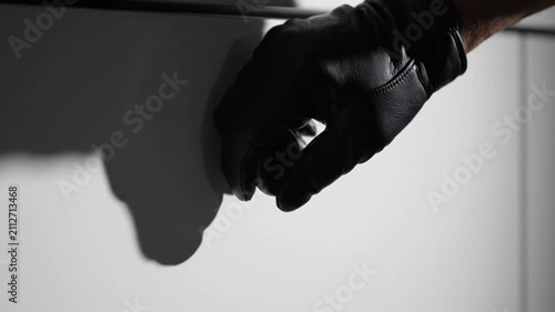 Hand in black leather glove turning a door knob