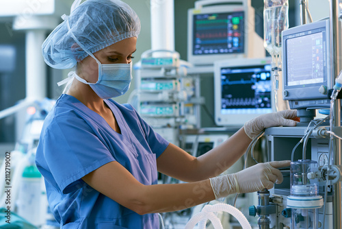 Female Anesthesiologist Monitoring Patient and Adjusting Anesthesia Machine During Surgery