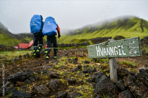 Hikers walking past Hvanngil signpost on Laugavegur trail, Iceland. 