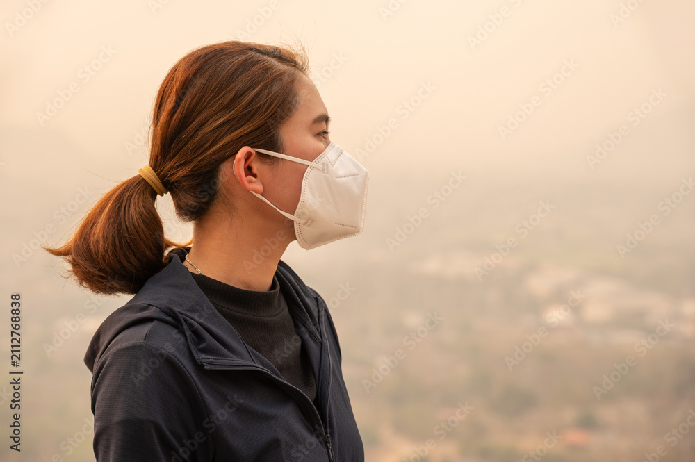 Obraz premium Asian woman wearing N95 mask for protect Bad air pollution (PM2.5). PM2.5 levels meaning the air quality posed a health hazard.