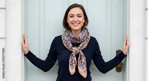 Cheerful Young Woman in Stylish Scarf Posing Happily at Home Front Door