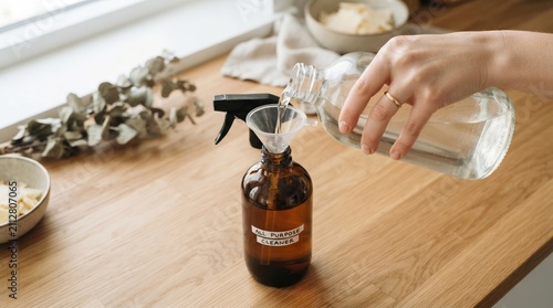 Making natural all-purpose cleaner at home, pouring liquid into a spray bottle using a small funnel