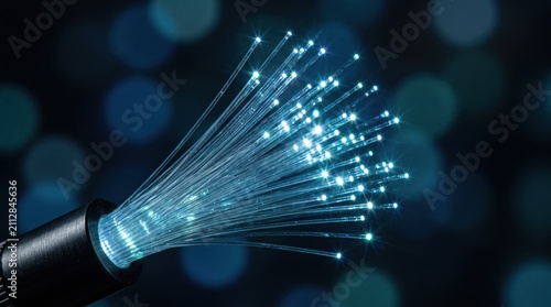 Fiber Optics Close-Up: A bundle of illuminated fiber optic strands glows brightly, emitting a soft blue light against a dark, bokeh-filled background.