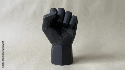 Black minimalist geometric fist sculpture on gray background.