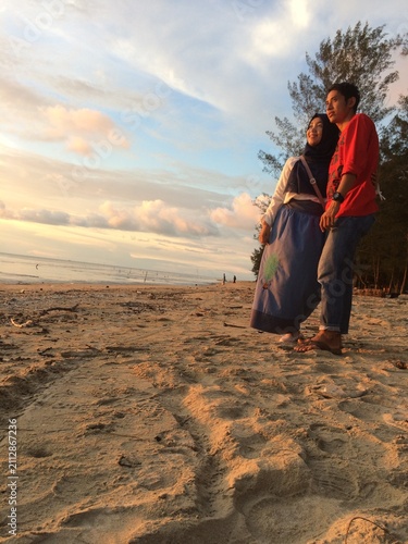 A couple is relaxing and enjoying the sunset at the beach.