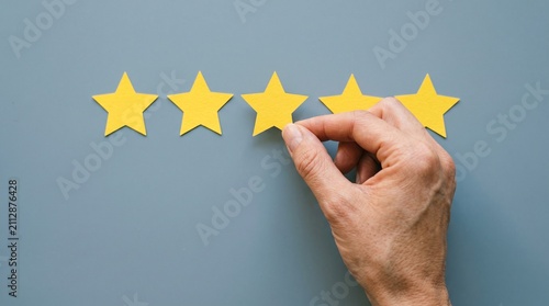 Five Star Rating: A hand carefully places the final golden star, completing a perfect five-star rating, symbolizing excellent quality and customer satisfaction.