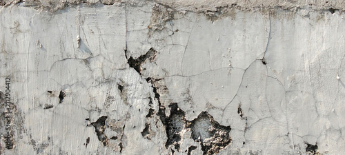 Cracked and peeling concrete wall texture against a weathered cement background.