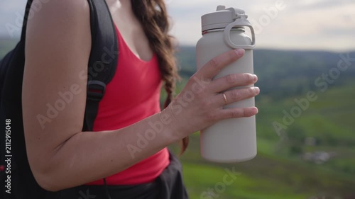 Hiking on green hills with a water bottle in hand during a sunny day