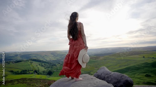 Standing on a rock with a view of the green hills at sunset in an open field