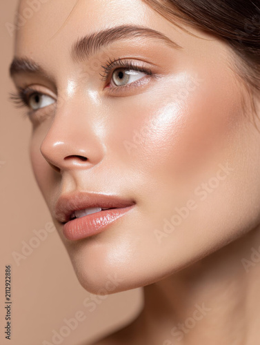 Woman with glowing skin and natural makeup looks serene in close up portrait. Her smooth complexion and subtle beauty are highlighted