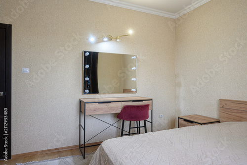 Bild auf Leinwand cozy bedroom features a bed with a wooden headboard, a vanity with a lighted mir