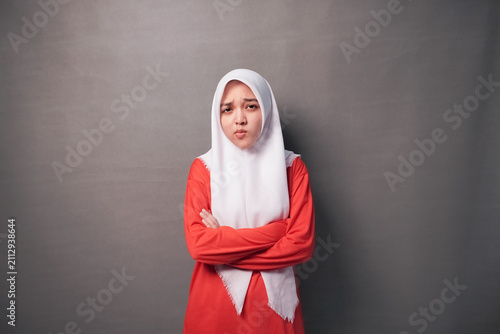 Принти на полотні Woman in red outfit and white hijab stands with arms crossed