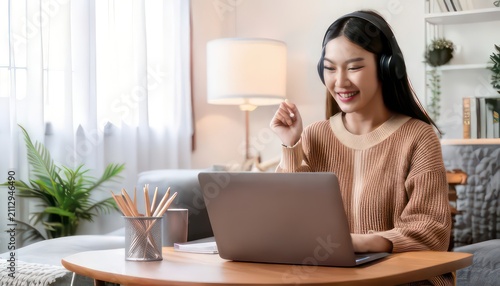 Young woman with headphones working on laptop in cozy home setting