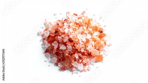 Coarse pink rock salt crystals piled on a white background
