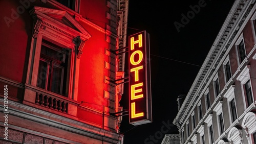 Moody neon-lit hotel sign glowing against urban night architecture