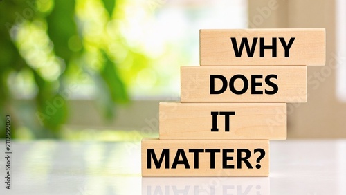Minimalist wooden blocks spelling why does it matter against blurred green background