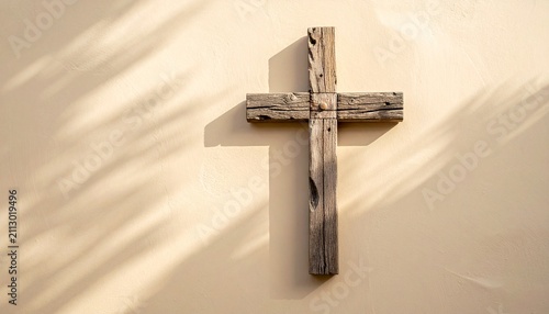 Rustic Wooden Cross Hanging on Beige Wall with Sunlight and Shadows