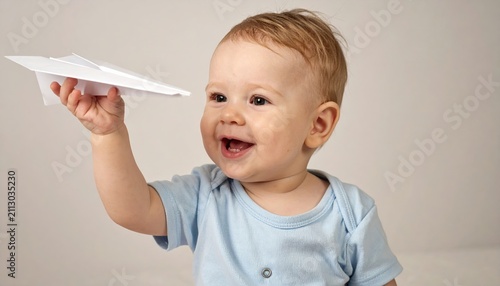 baby boy holding paper airplane smiling