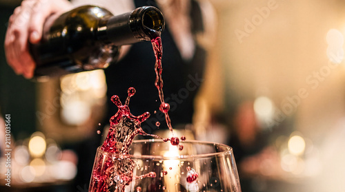 Wine Pour: A sommelier carefully pours rich red wine into a glass, creating an elegant splash as the liquid cascades, hinting at a sophisticated tasting experience.