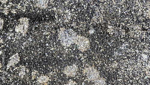 Macro view of glittering mineral fragments in dark volcanic stone texture background.