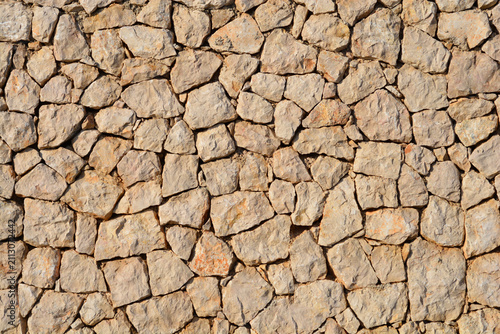 Bild auf Leinwand A detailed background shows a traditional Mediterranean dry stone wall made of n