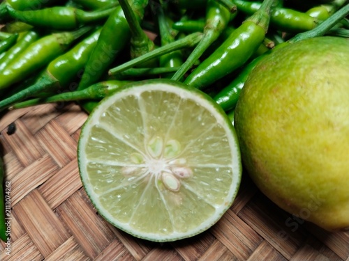 Foto A lime is being cut in half on a bamboo tray, alongside green bird's-eye chilies