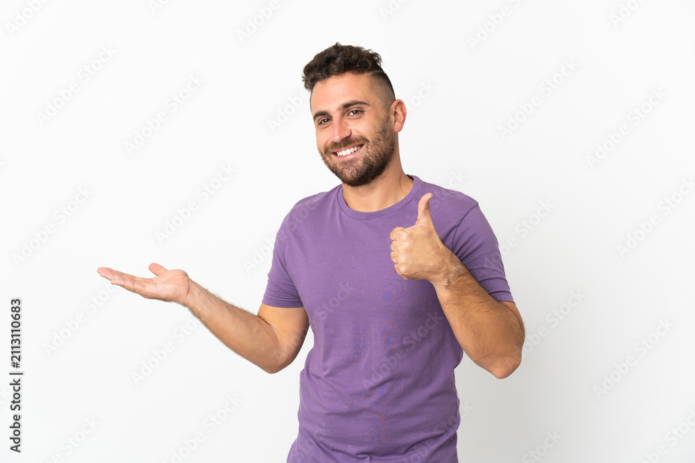 Naklejka premium Caucasian man isolated on white background holding copyspace imaginary on the palm to insert an ad and with thumbs up