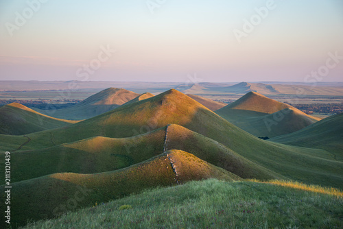 Summer sunset at Dolgiye Mountains in the Orenburg region, Russia. Hilly terrain, mountain fields. The beginning of the Ural Mountains.
