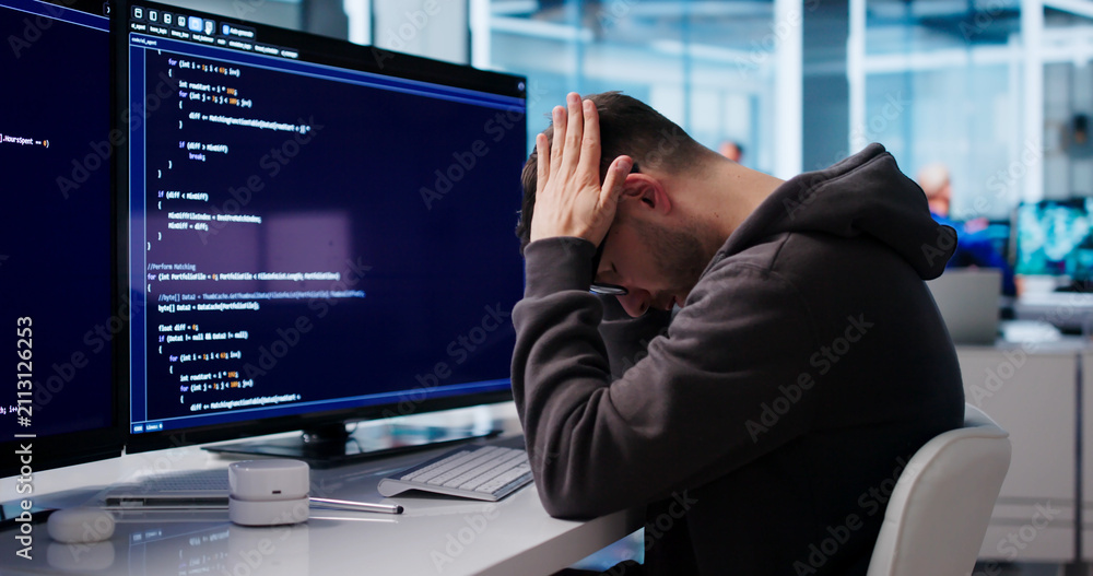Fototapeta premium Young Software Engineer Looks Tired And Stressed While Coding