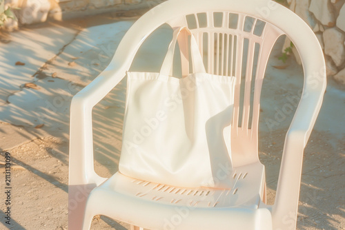 Blank white canvas tote bag mockup on white plastic chair