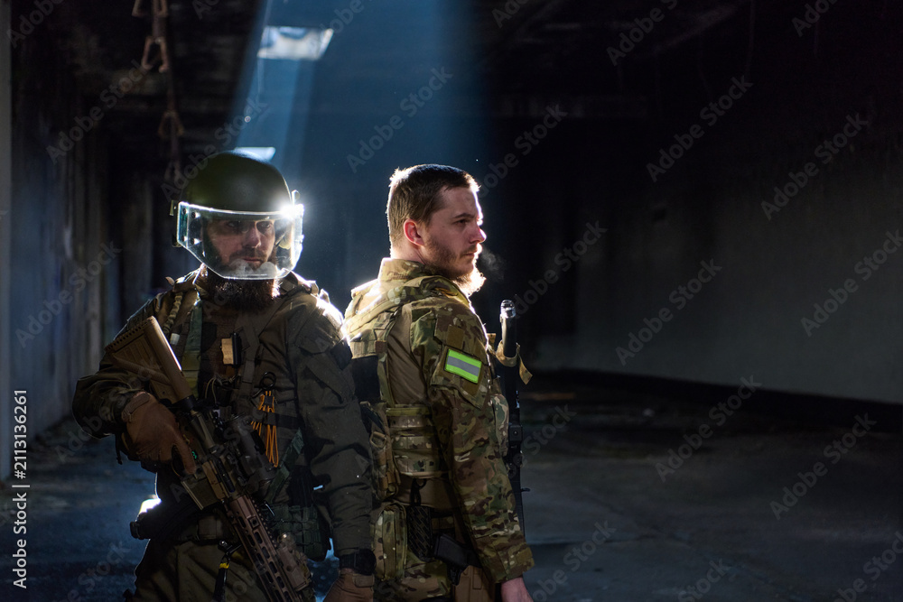 Obraz premium Two Tactical Soldiers Back-to-Back in Urban Ruin With Rifles and Protective Gear