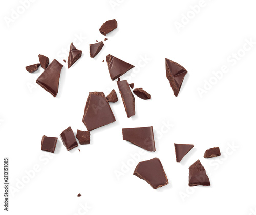 Several irregular pieces of dark chocolate are scattered across a white background. Chocolate pieces isolated. 