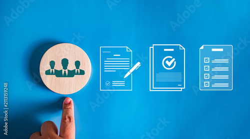 Hand pointing to wooden block with people icon next to virtual document agreement, contract, and checklist icons, concept of team onboarding and HR compliance