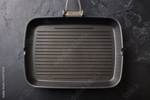 Empty grill pan on black textured stone background top view. Close up. Top view.