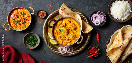 Indian curry with naan bread, rice and garnishes. Dark grey background. Top view.