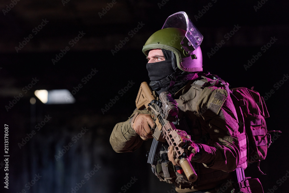 Obraz premium Tactical Soldier In Helmet And Balaclava Holding Assault Rifle During Night Urban Operation