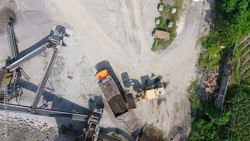 Aerial top view of wheel loader loading dump truck with sand and gravel at aggregate processing plant