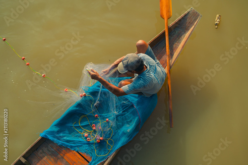 Obraz na plátně Fishing activity in Surat Thani Thailand on a calm river in a traditional boat