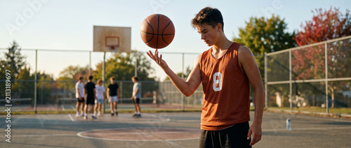 Teenager spinning basketball while standing on outdoor court  