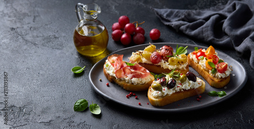 Foto Assorted Italian bruschetta platter with prosciutto, tomatoes, cream cheese and olives