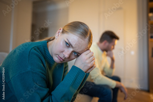 Obraz na płótnie Stressed married couple sitting on couch distancing from each other after emotional family argument, frustrated woman in offence to partner, emotional crisis, coldness and mistrust in relationships