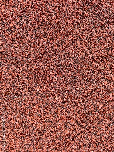 High-angle view of a textured red and black rubber surface from a sports running track. Perfect for abstract sports backgrounds or industrial material concepts.