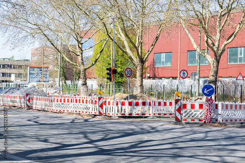 Straßenbaustelle mit Absperrungen unter alten Stadtbäumen