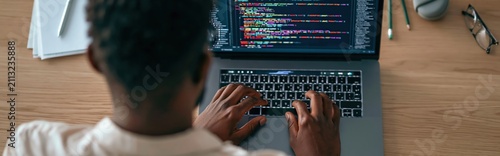 Developer and programmer coding software on a laptop at a modern office workspace
