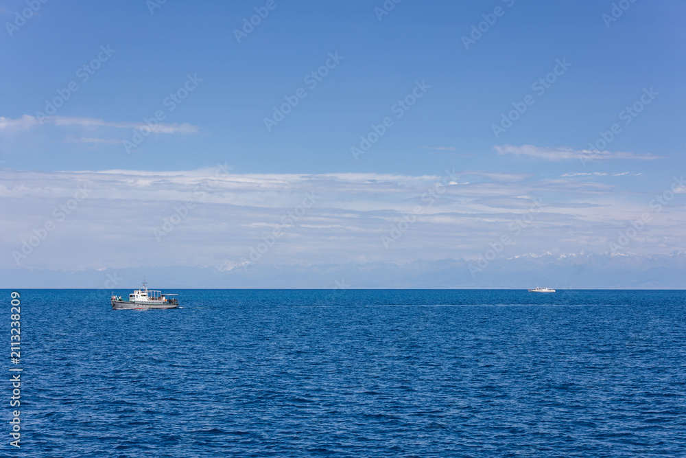 Obraz premium Two boats sailing on tranquil lake with mountains in background