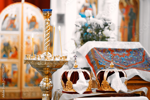 Fotografie Golden Orthodox wedding crowns sit on decorated altar beside lit candles and emb