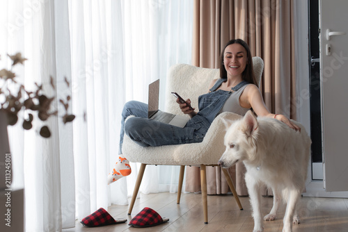 Foto Happy woman pets dog interrupting remote work at home