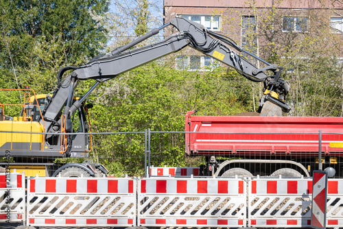 Bagger belädt Kipplaster mit Erdreich auf einer Baustelle
